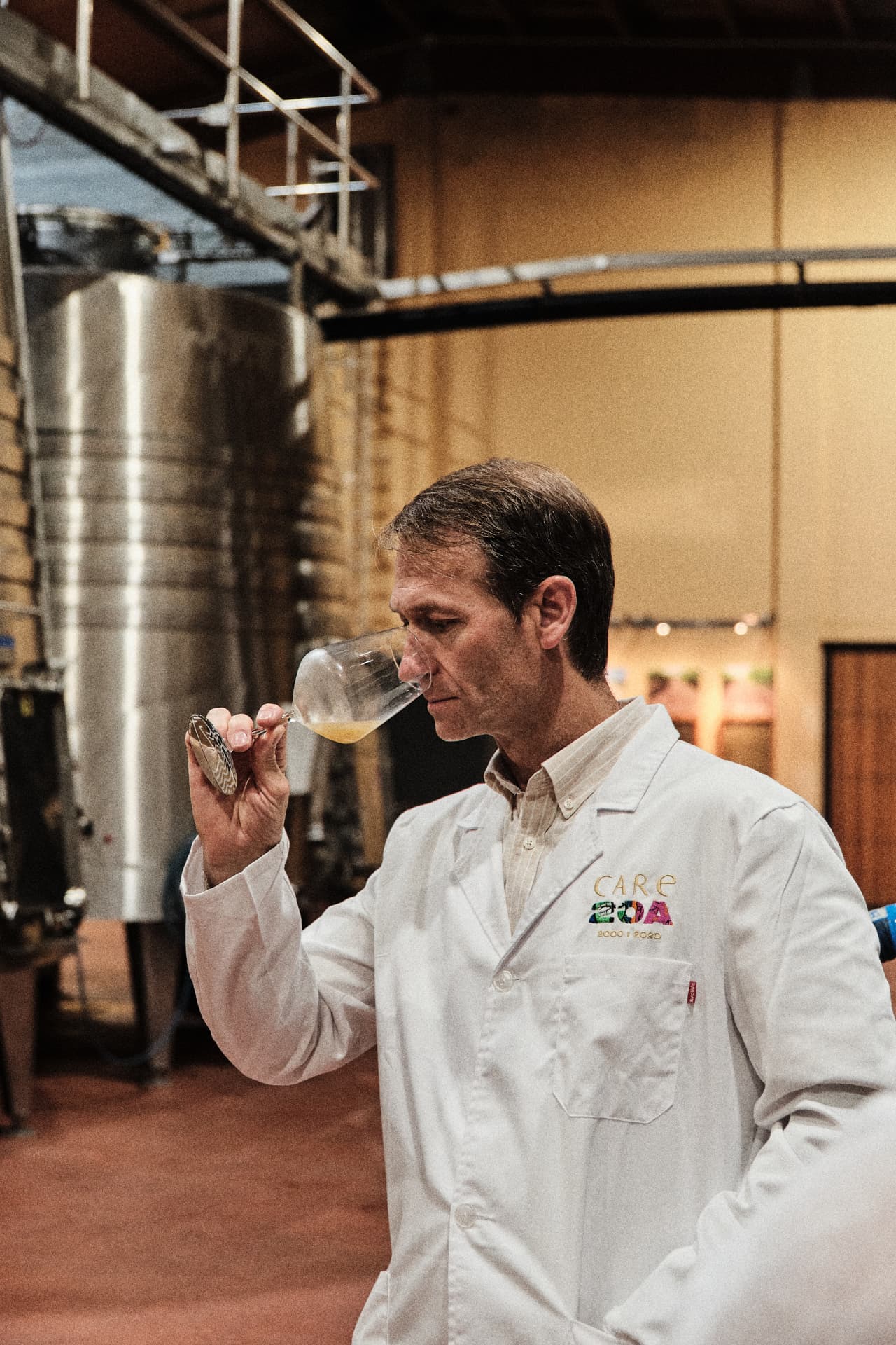 Enólogo catando vino junto a los depósitos