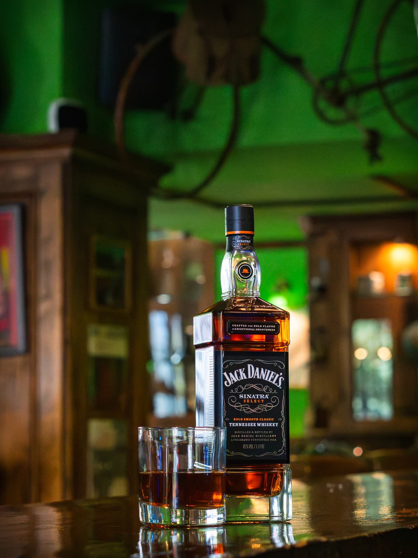 Botella de whisky y dos vasos servidos en la barra