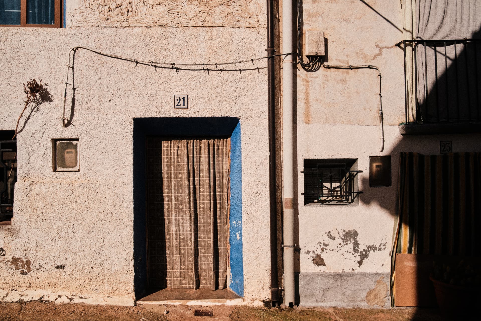 Fachada de una casa del pueblo con cortina en la puerta