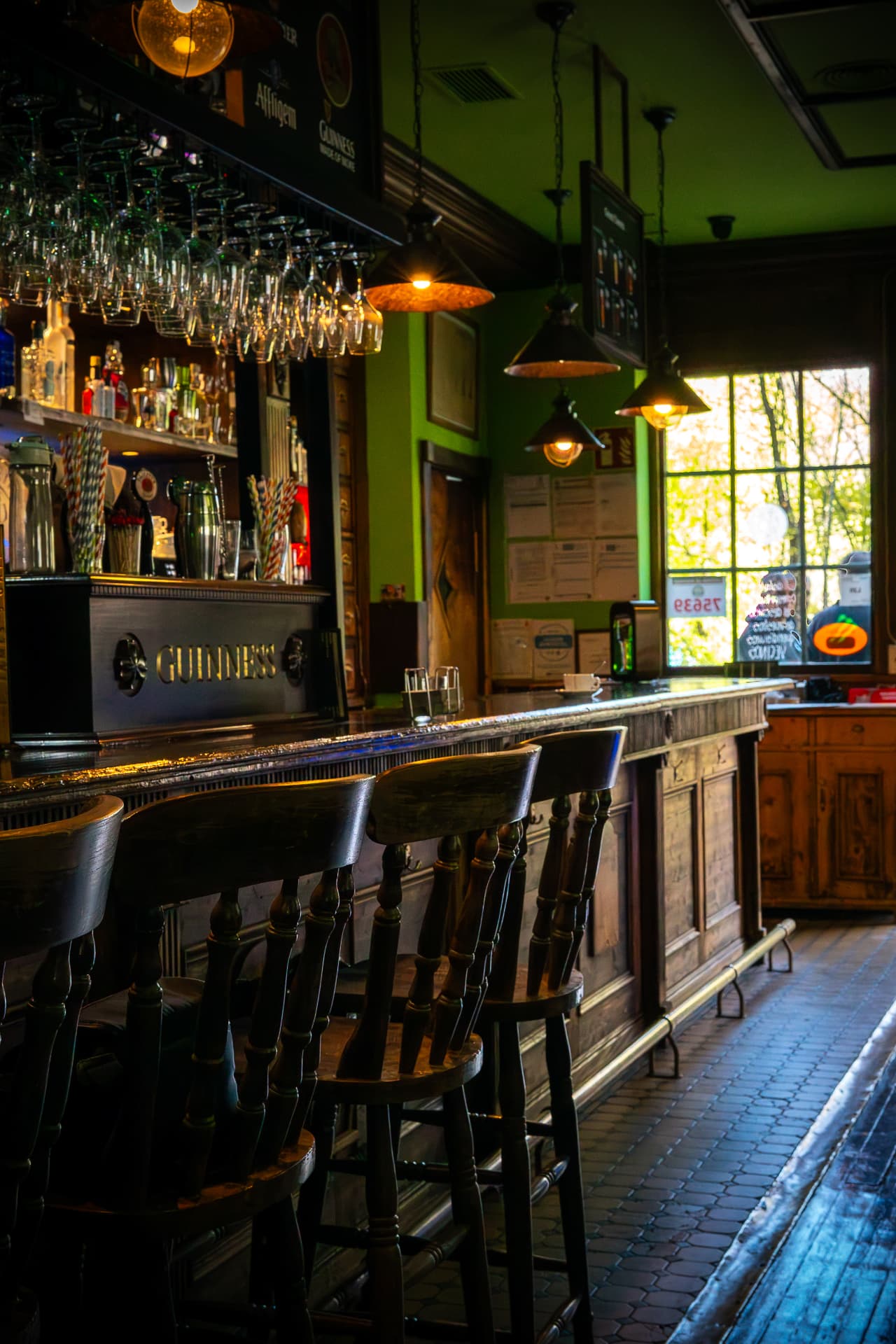 Barra del pub con taburetes de madera y copas colgadas