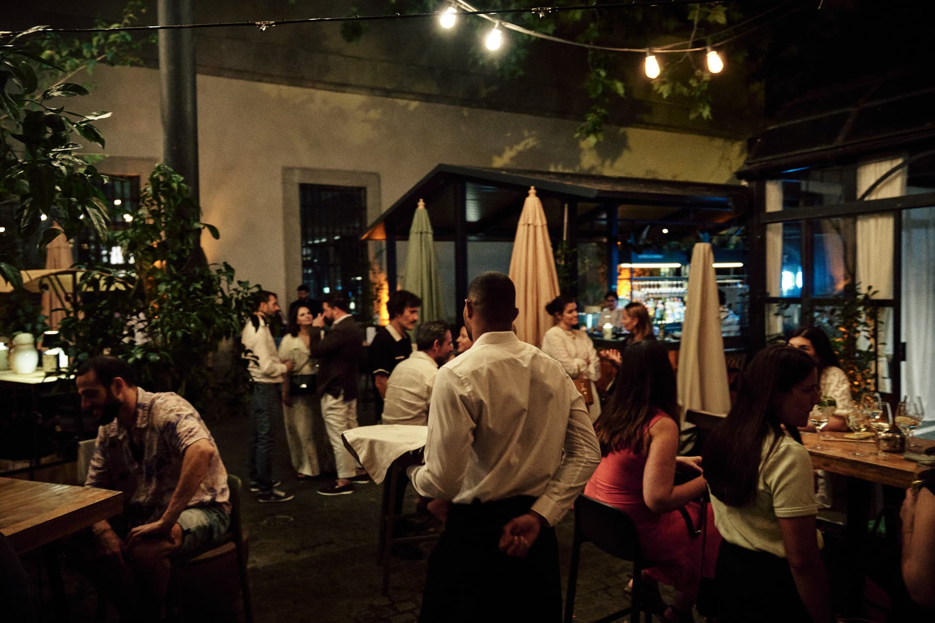 Terraza de noche con guirnaldas de luces y gente en las mesas