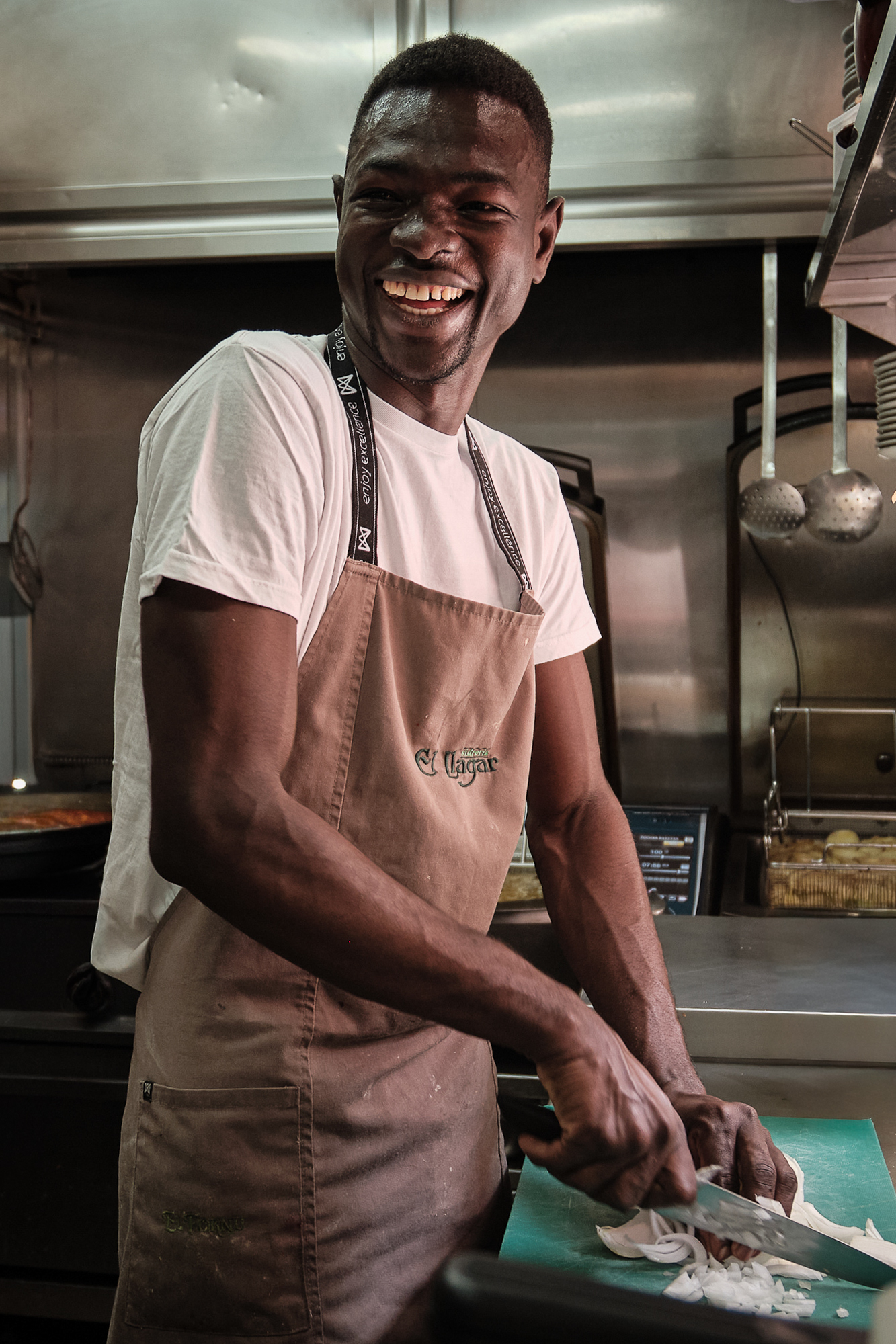 Cocinero sonriendo mientras corta cebolla en la cocina