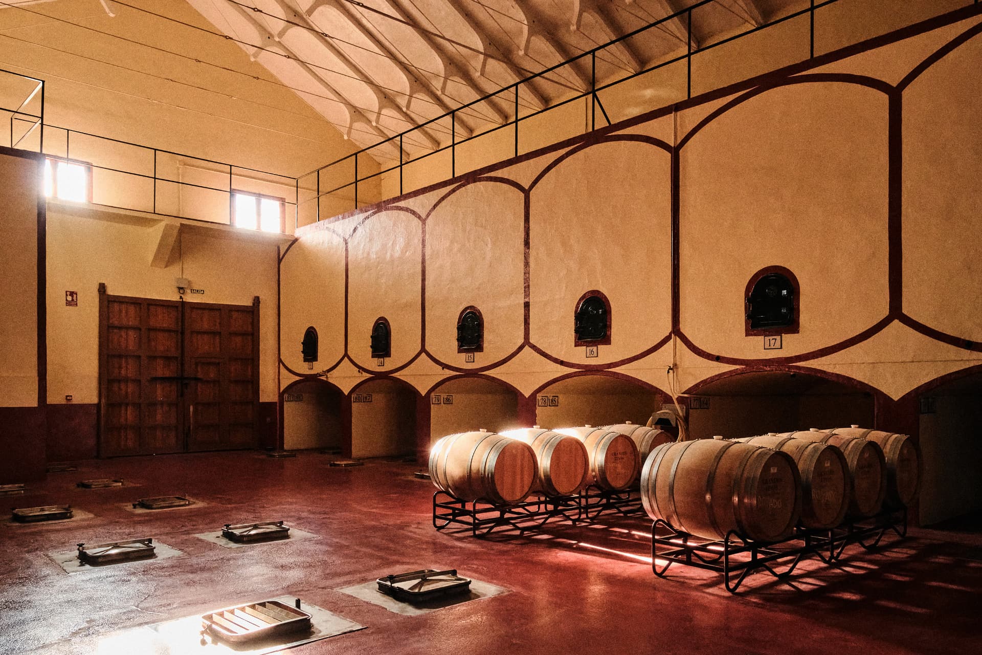 Nave de la bodega con arcos pintados y barricas alineadas