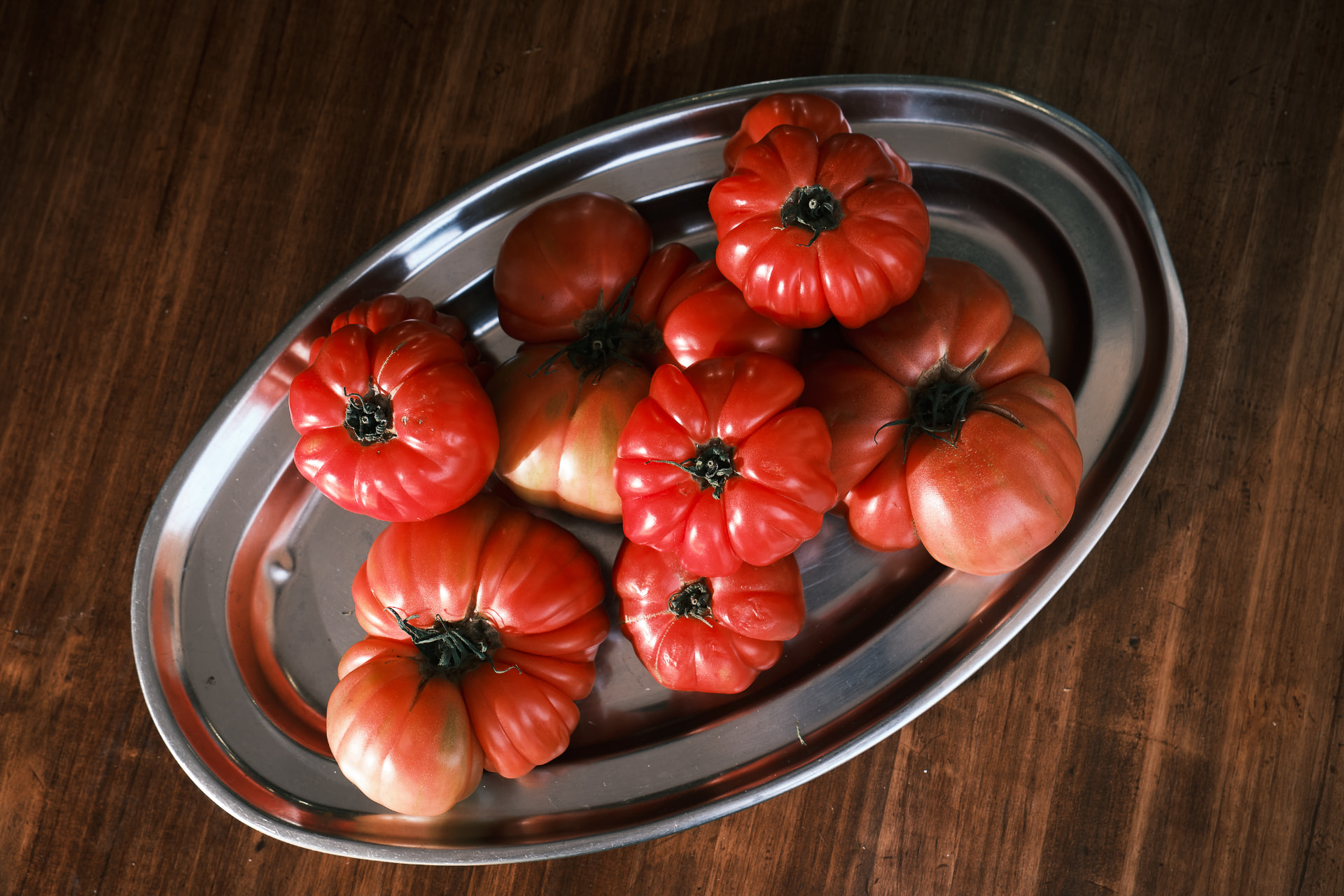 Tomates de pera en una bandeja metálica sobre mesa de madera