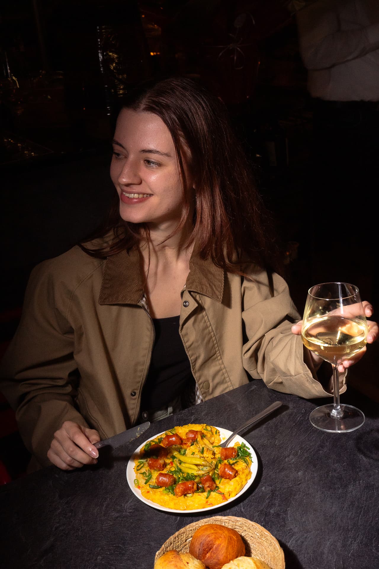 Mujer con una copa de vino blanco junto a un plato de arroz