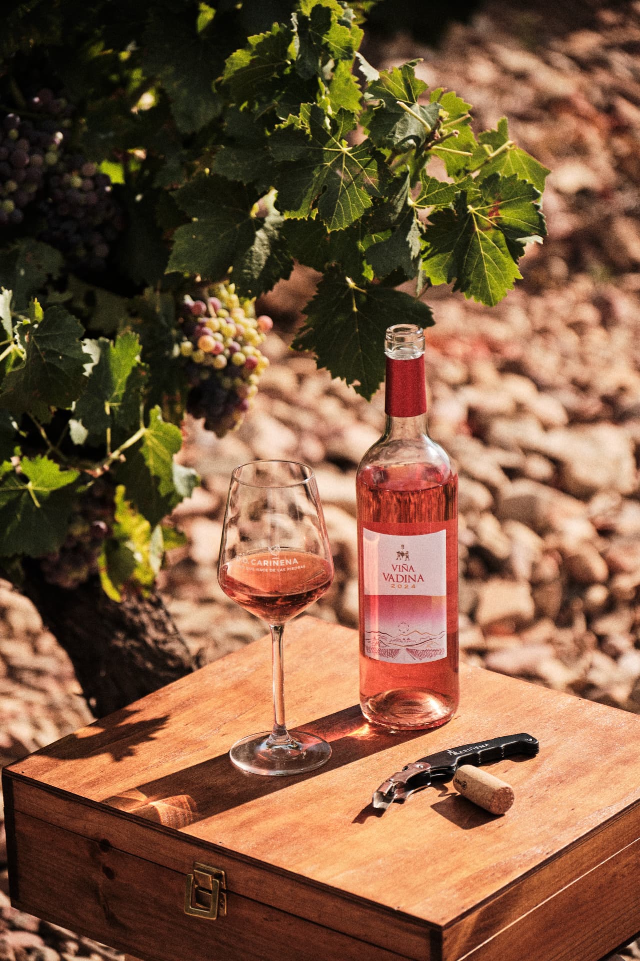 Botella y copa de vino rosado sobre una caja de madera