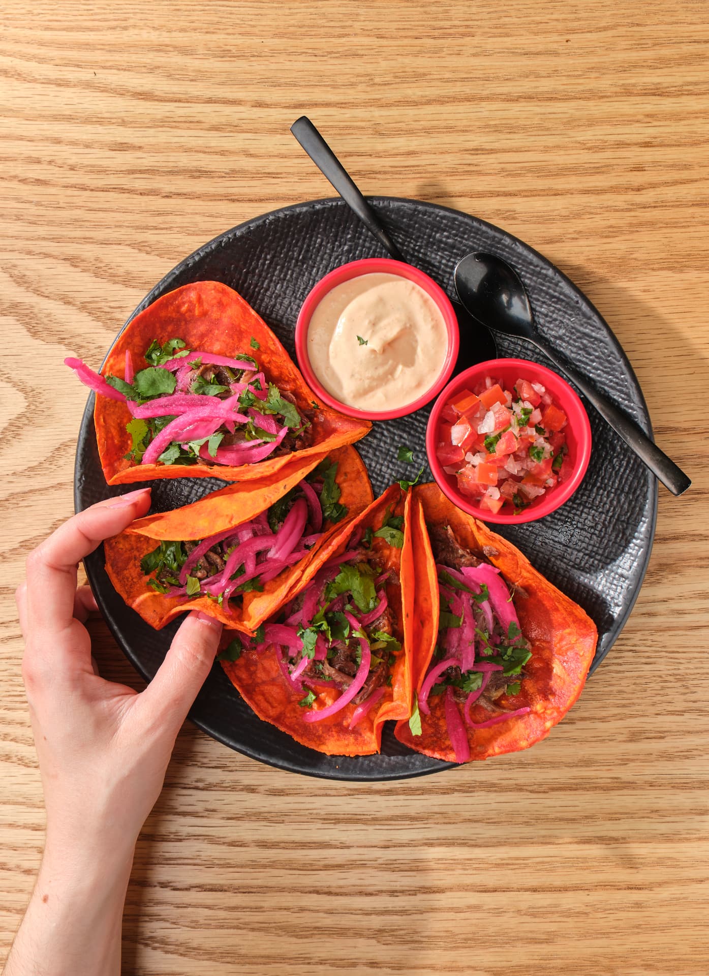 Plato de tacos con carne, cebolla encurtida y dos salsas