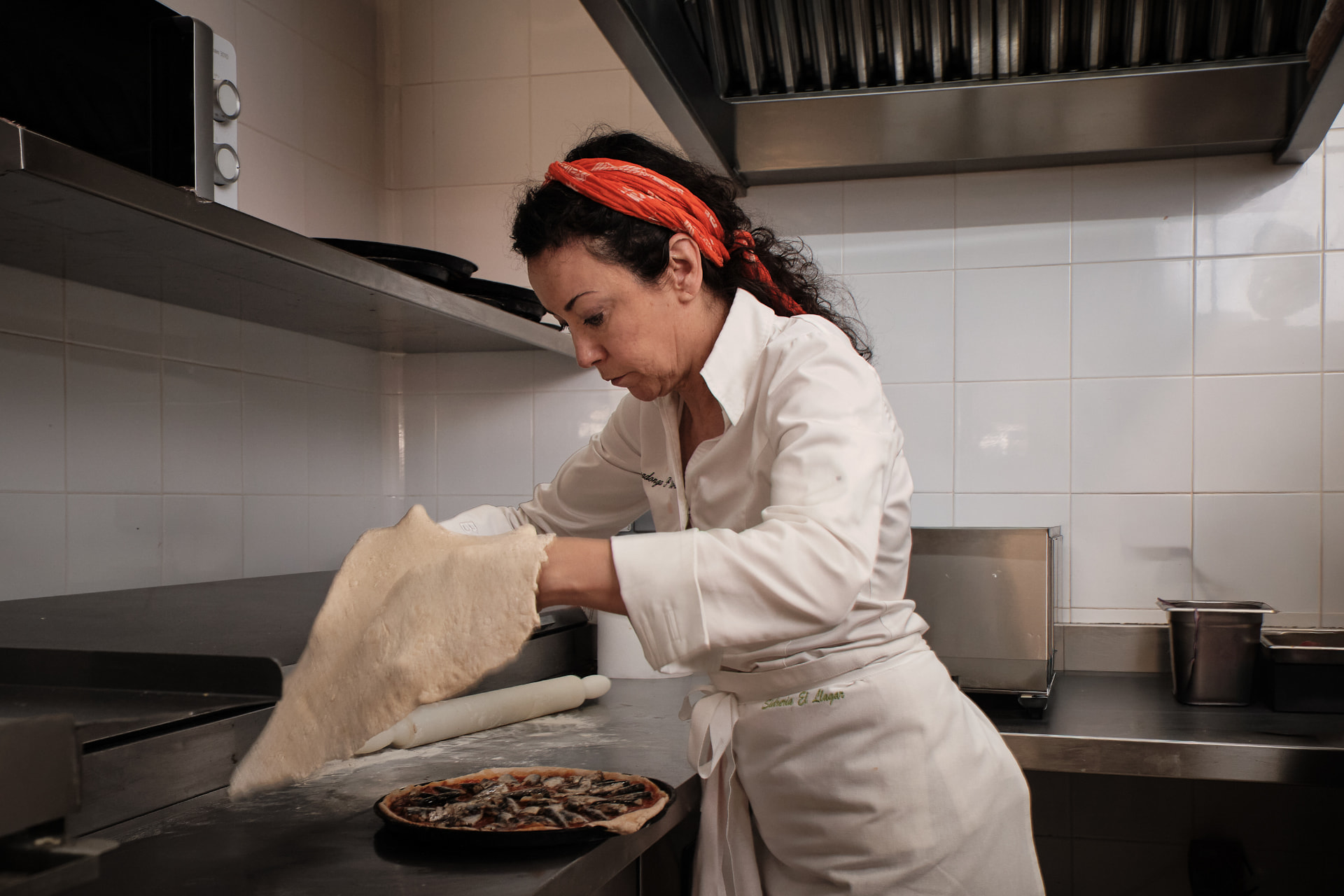 Cocinera estirando masa de pizza en la cocina